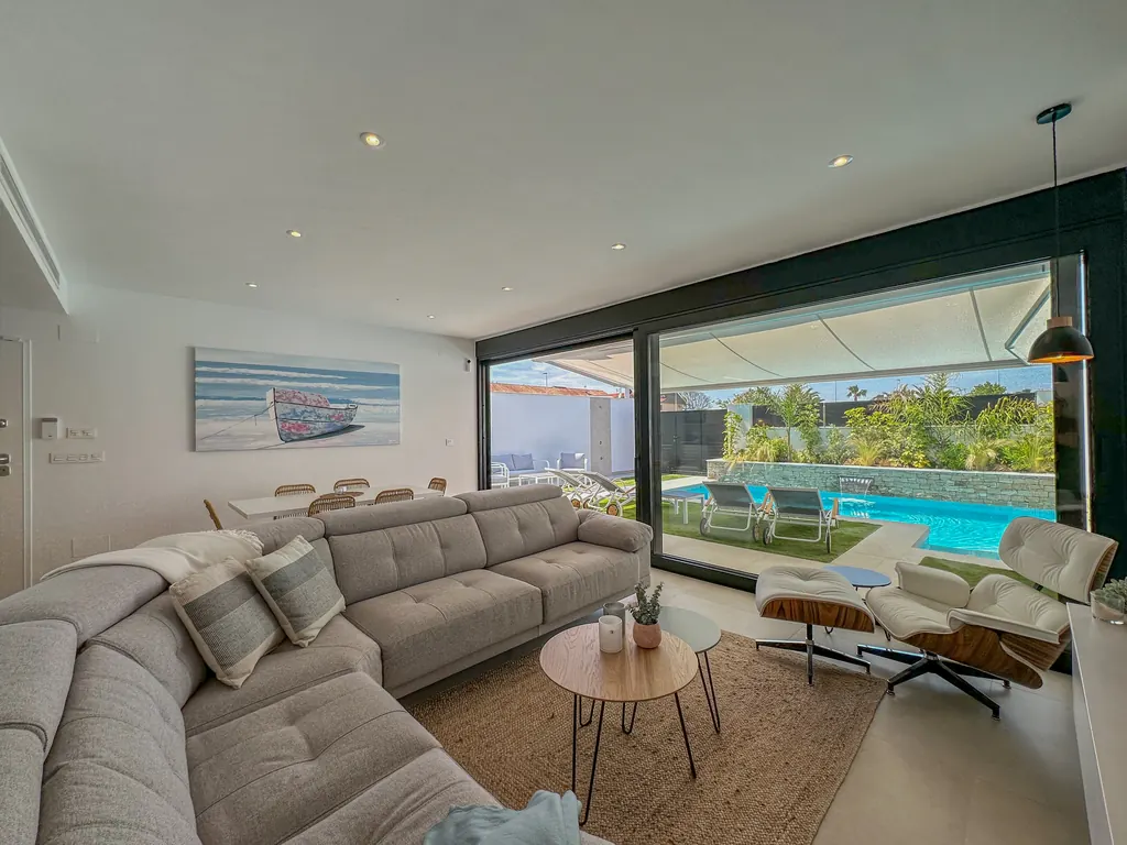 Séjour contemporain ouvert par une grande baie vitrée sur la terrasse et la piscine