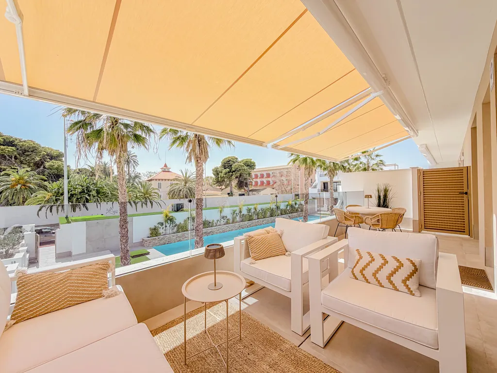 Terrasse couverte avec salon d'extérieur, vue sur les palmiers et la piscine