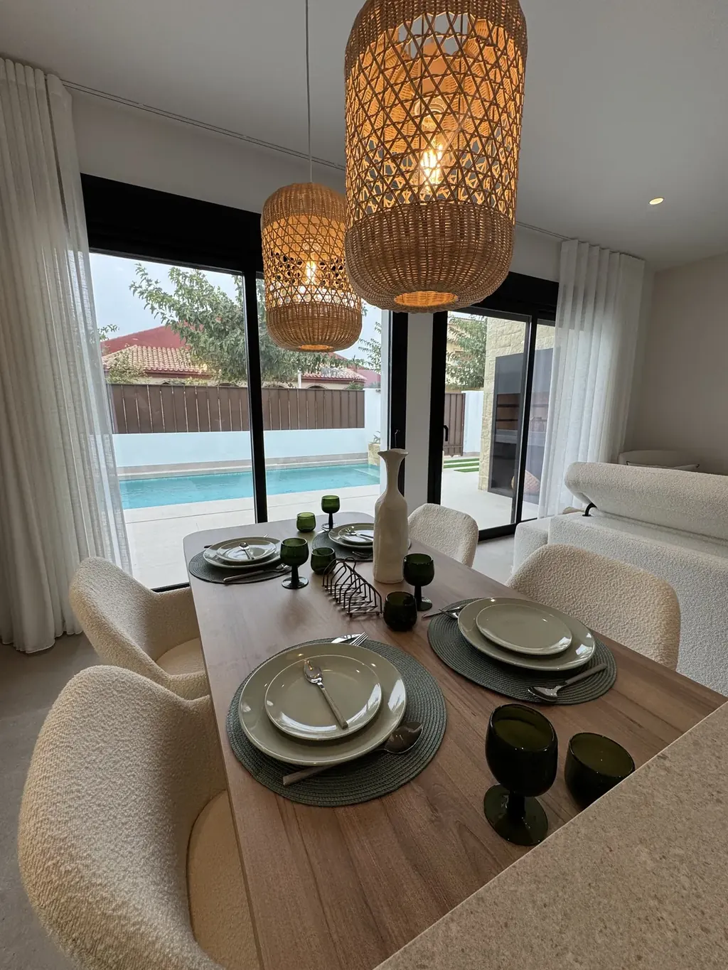 Salon lumineux d'une villa neuve ouvert par de grandes baies vitrées sur la piscine et le jardin